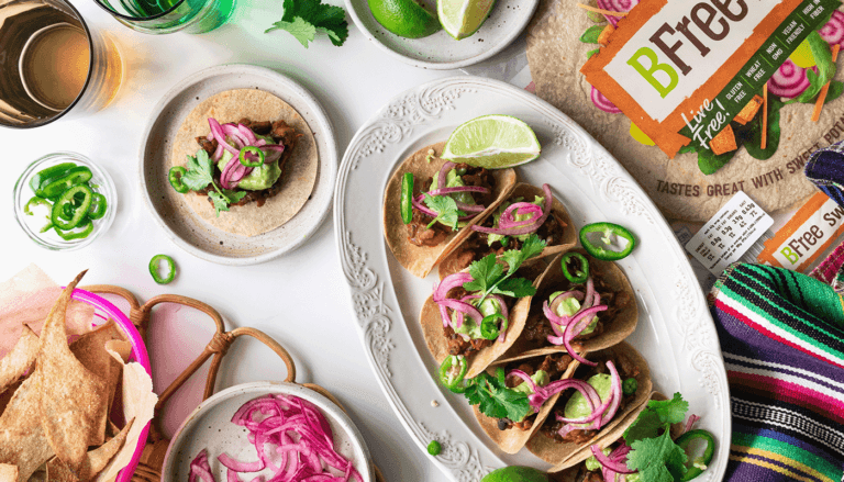 Photo of vegan refried been tacos including pickled onions and vibrant chillis and gluten free sweet potato wraps.