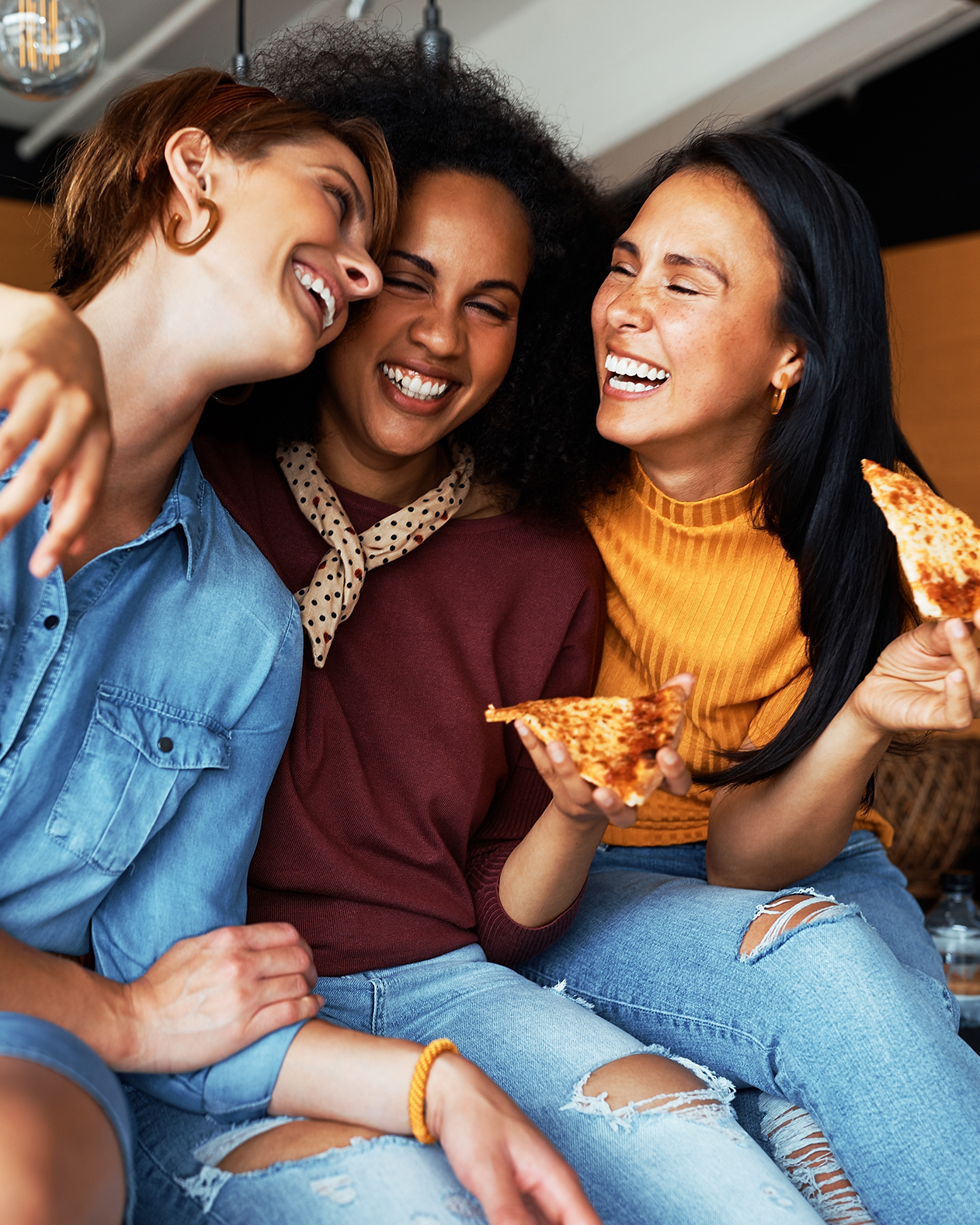 3 ladies laughing holding pizza